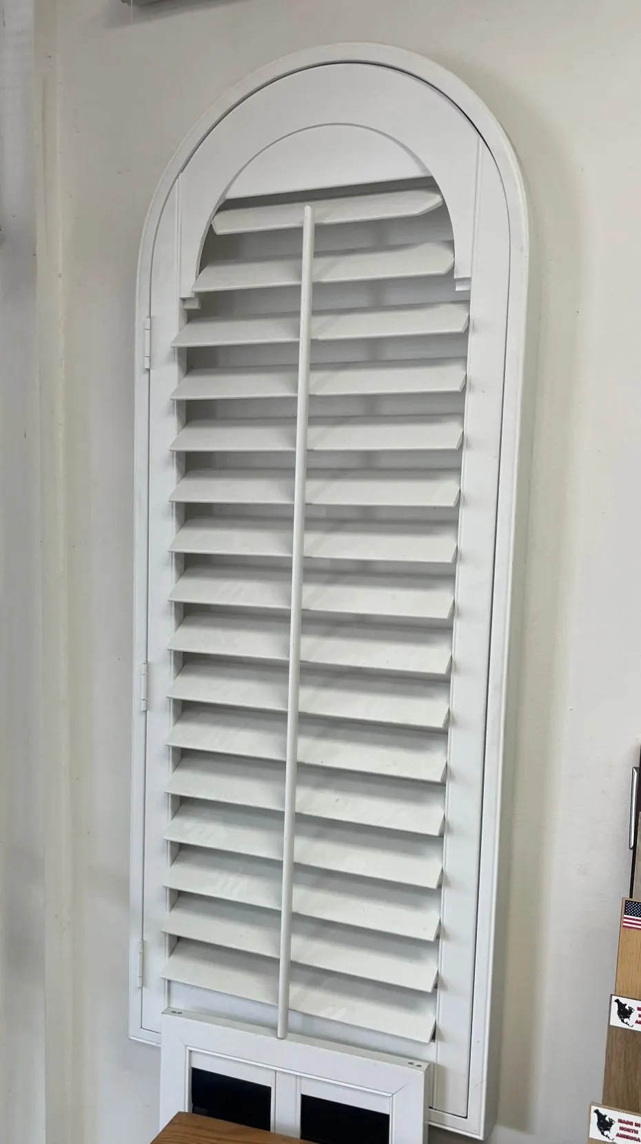 White arched plantation shutter on display in the Angelo's showroom